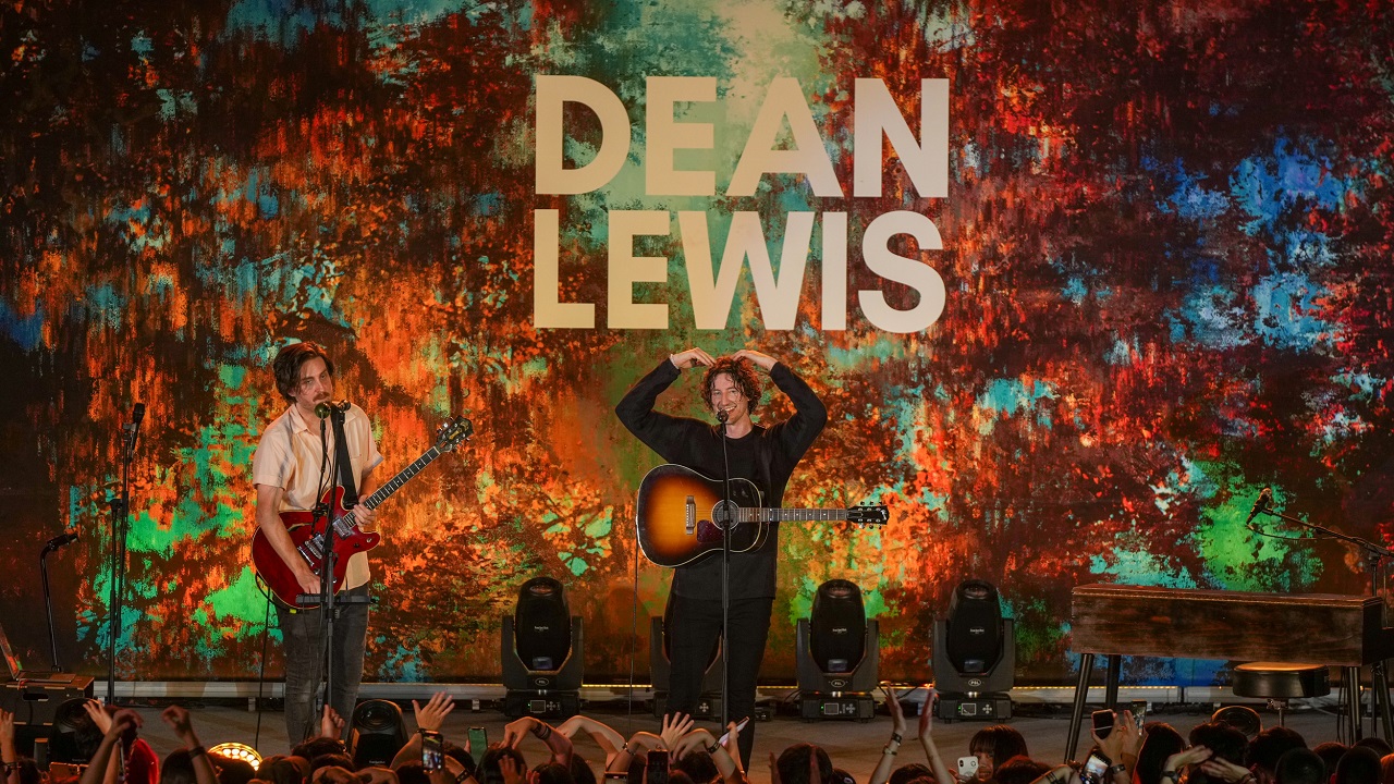 Dean Lewis on stage doing a heart 