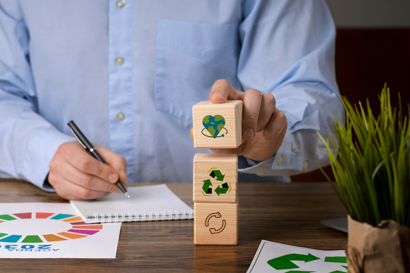 Front view of man with wooden blocks showing sustainability symbols