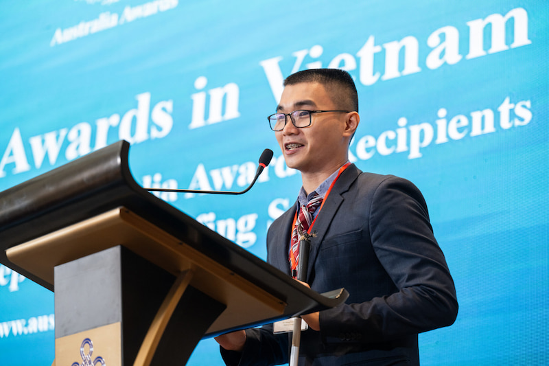 Minh speaking at a podium