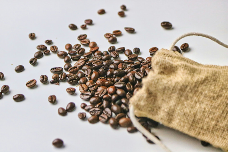 Roasted coffee beans spill from a bag