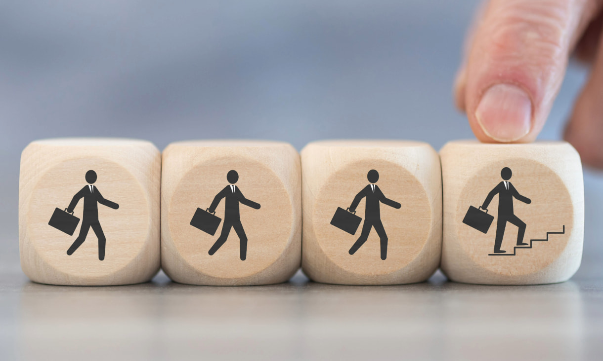 four wooden dices with a businessman in suit and briefcase walking illustrating career advancement